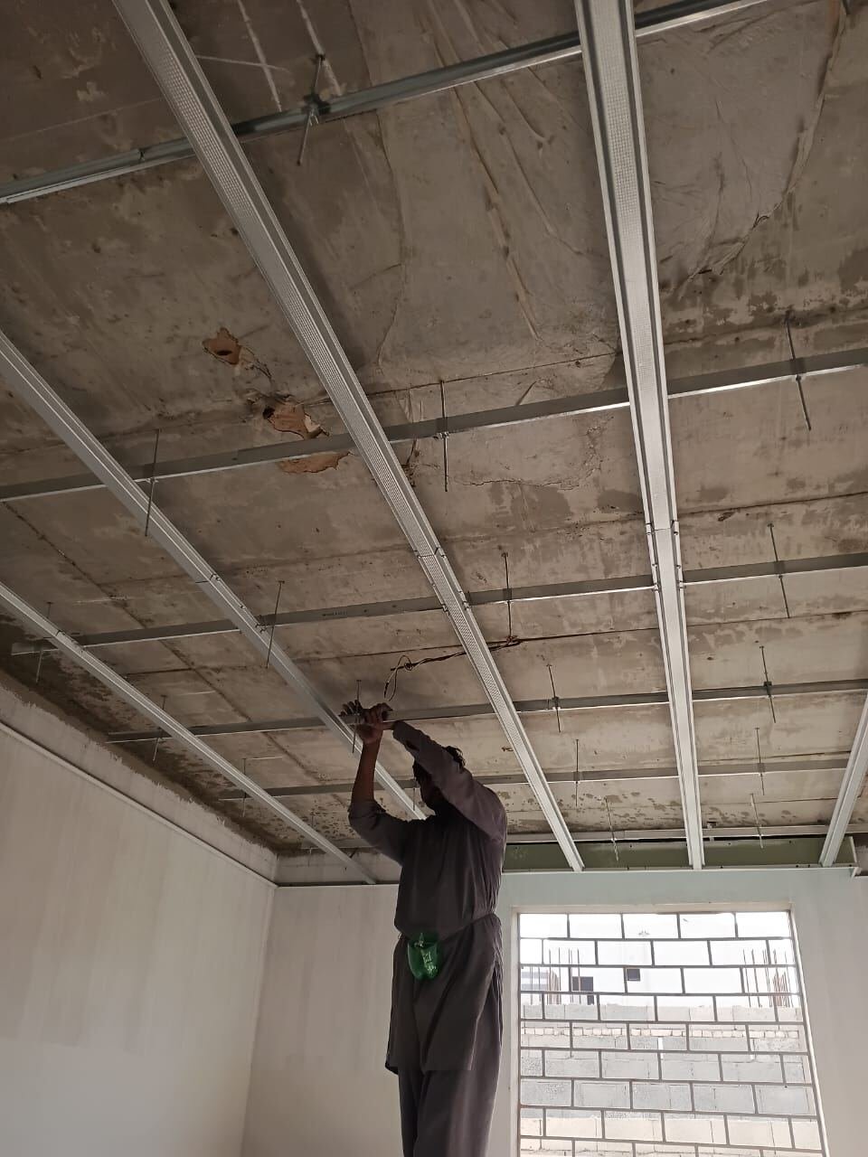 Technician installing a gypsum board ceiling frame